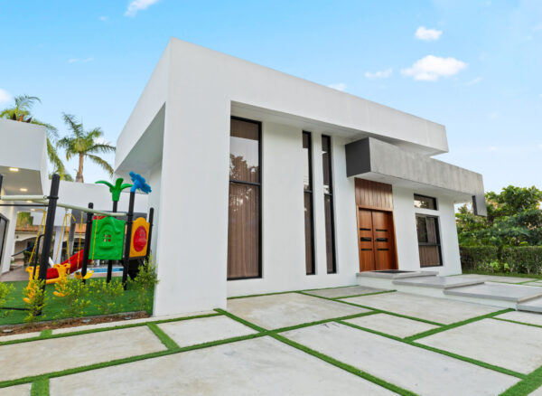 A bright sunny day with a blue sky and clouds, featuring an outdoor house view